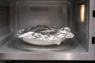 Plat recouvert de papier aluminium placé dans un four à micro-ondes