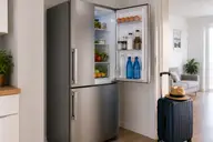 Réfrigérateur ouvert dans une cuisine avec valise prête pour un départ en vacances