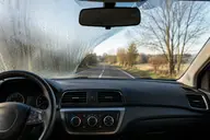 Pare-brise de voiture en cours de désembuage avec une zone redevenue nette